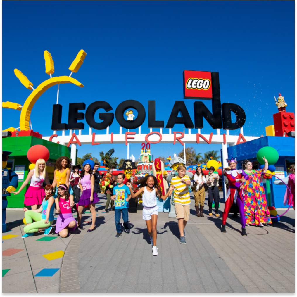 Picture of children and mascots walking out the front of Legoland.